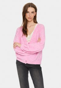 Ljusrosa, oversized V-ringad cardigan med långa ärmar och ribbad mudd. Har en enkel knäppning med en knapp och är tillverkad av ett mjukt, strukturerat material.