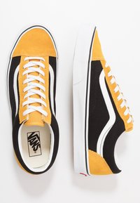 Black and yellow Vans sneakers featuring a suede and canvas upper, white laces, and signature side stripe design, with a white rubber sole.