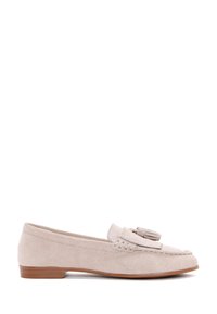 Mocasines de ante beige claro con punta redondeada, borlas decorativas y un bajo tacón marrón. Textura suave con detalles de costura.