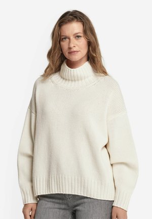 Sweter dziany w kremowym kolorze z wysokim, prążkowanym golfem. Posiada opadające ramiona i luźny krój, z prążkowanymi mankietami i dołem.
