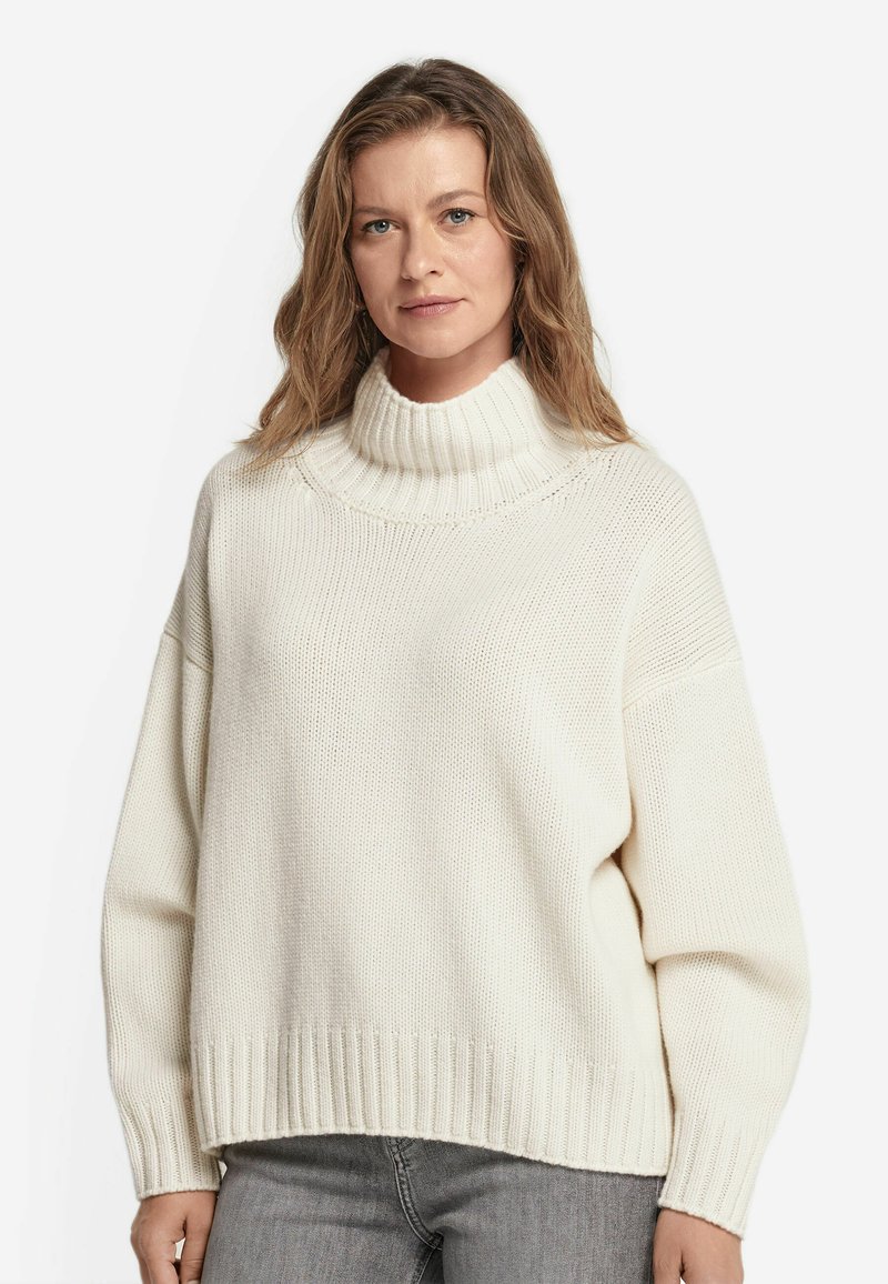 Strickpullover in Creme mit einem hohen, gerippten Rollkragen. Hat überschnittene Schultern und eine lockere Passform, mit geripptem Saum und Ärmelsäumen.