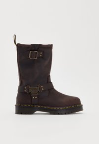 Brown leather knee-high boot with buckle detail, yellow stitching along the sole, and a textured finish. Features pull tab for easy wear.
