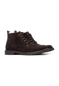 Botas de tobillo de ante marrón oscuro con diseño de cordones, costuras naranjas contrastantes y una suela de goma texturizada.