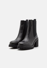 Black leather ankle boots with a smooth finish, elastic side panels, chunky textured sole, and a high block heel.