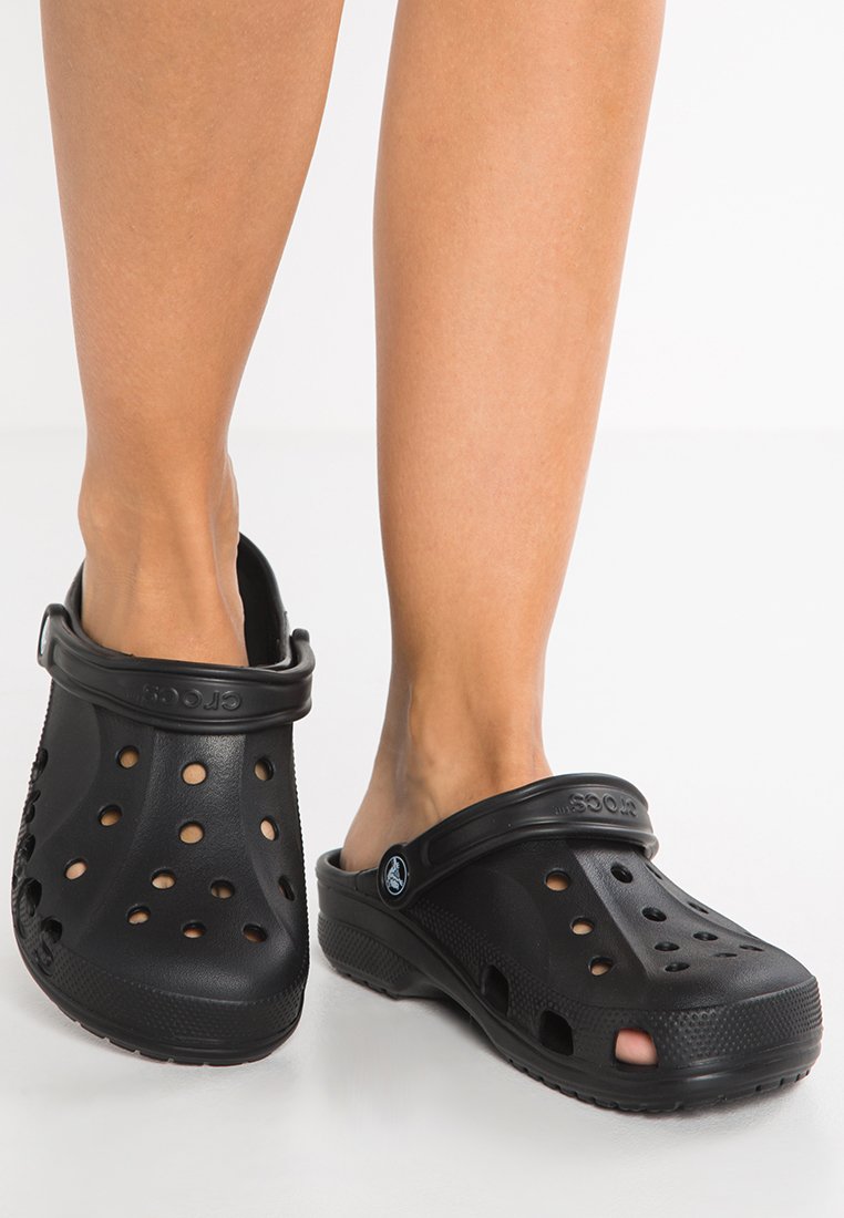 Los zuecos de goma negra cuentan con agujeros de ventilación, una correa trasera y una suela texturizada. El diseño es ligero y fácil de limpiar.