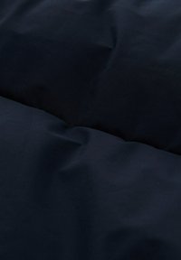 Tessuto per biancheria da letto di un blu navy scuro con una texture liscia, caratterizzato da un aspetto leggermente stropicciato e un design minimalista. Nessun motivo o hardware visibile.