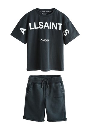 Camiseta negra de manga corta con el texto "ALLSAINTS LONDON" combinada con pantalones cortos negros con cordón que presentan un sutil logo de "ALLSAINTS" en el bolsillo.