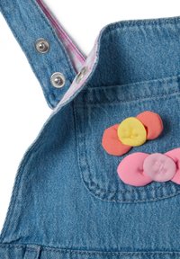 Denim tuinbroeken hebben metalen drukknoopsluiting en een roze geruite voering, versierd met kleurrijke stoffen knopen in gele, roze en oranje vormen.