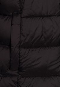 Svart puffjacka av tyg med kviltad design, med en slät yta och horisontella sömmar som betonar värme och isolering.