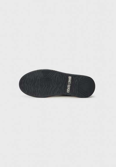 Black shoe sole with textured tread pattern and "roberto cavalli" logo printed in white near the heel on a plain gray background.