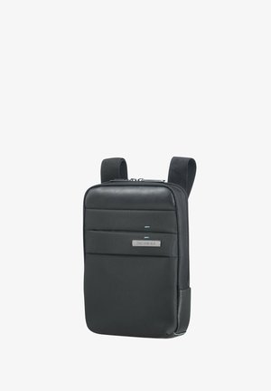 Sac à dos noir avec tissu texturé, doté d'une poche avant avec une surface lisse et une plaque de logo. Sangles réglables pour un transport confortable.