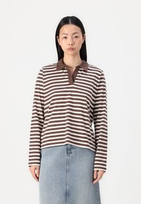 Brown and white striped long-sleeve polo shirt with a solid brown collar, paired with a light blue denim skirt.