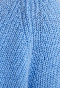 Light blue knitted fabric with a textured, ribbed pattern. The fibers appear soft and fuzzy, creating a cozy appearance.