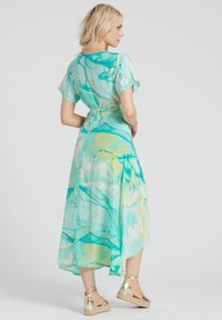 Un vestido fluido, a la altura de la rodilla, en aqua con patrones abstractos en verde y dorado, que presenta mangas cortas y una cintura ceñida para un look ajustado.