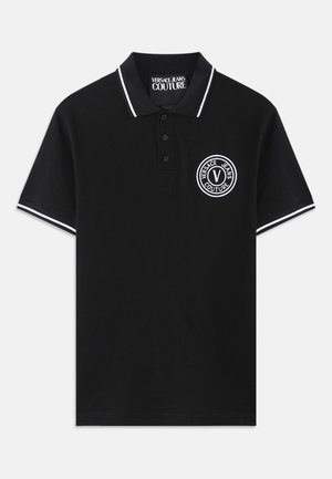 Črn polo majica s kratkimi rokavi z belim robom na ovratniku in rokavih, z zapenjanjem na tri gumbe in okroglo oznako Versace Jeans Couture na prsih.
