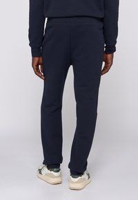 Granatowe dresy wykonane z miękkiego materiału, slim fit, elastyczny pas i zwężane nogawki. Noszone z trampkami, co podkreśla komfort i swobodę ruchów.