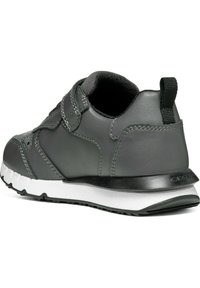 Zapatilla de cuero gris con acabado texturizado, correa de Velcro, collar acolchado, suela blanca y tirador en la parte trasera.