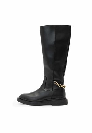 Botte noire en cuir, montant jusqu'au genou, avec une finition lisse, un bout arrondi et un accent en chaîne dorée près de la cheville. Semelle épaisse et texturée.