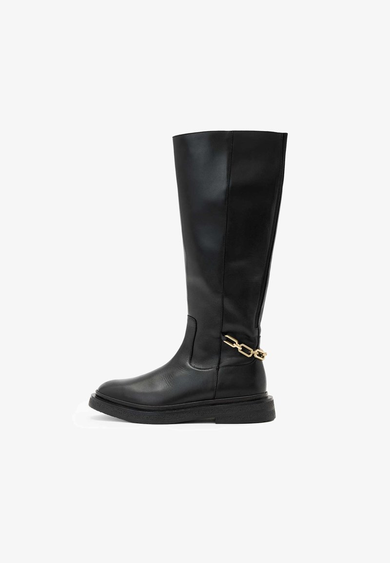 Czarny skórzany kozaczek do kolan o gładkim wykończeniu, zaokrąglonym nosku i złotym łańcuszku w okolicy kostki. Gruba, teksturowana podeszwa.