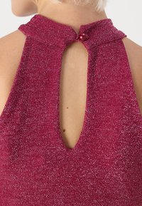 Μαγέντα αμάνικο τοπ με υφητή, λαμπερή επιφάνεια, διαθέτει άνοιγμα στην πλάτη και στρογγυλό κουμπί στο λαιμό.