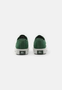 Zelene suede tenisice s bijelim gumenim potplatima i petama. Lacoste logo na peti. Zaobljen oblik s kontrastnim šavovima.