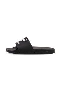Svart slide sandal med bred rem och vit logotypdetalj, platt fotsäng och texturerad yttersula. Tillverkad av syntetiskt material.