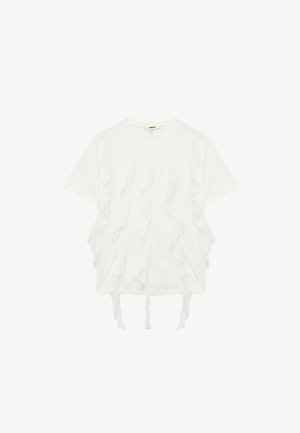 Camiseta blanca de manga corta con volantes en capas a lo largo de los lados frontales y lazos en el dobladillo inferior. Tejido suave, corte relajado.