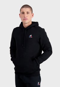 Sudadera negra con cordones, bolsillo frontal y logo bordado. Fabricada en tejido suave, con un corte regular y puños acanalados.