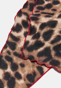 Dyreprint tørklæde med en beige og brun farvepalette og sorte leopardpletter. Scalloped kanter med rød kant accentuerer designet.
