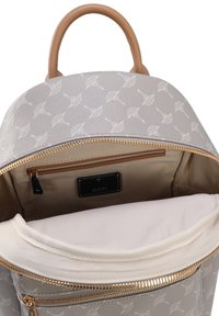 Mochila de cuero gris con un patrón floral blanco, cremalleras doradas y un asa beige. En el interior cuenta con un forro beige y un bolsillo con cremallera.