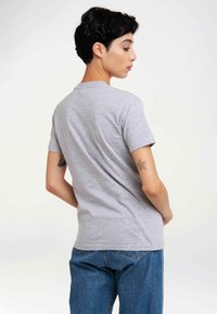 Gray short-sleeve t-shirt with a round neckline, displayed on a person from the back, paired with blue denim jeans.