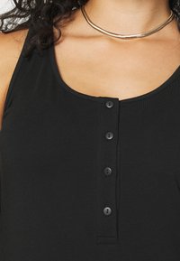 Schwarzes Tanktop mit Rundhalsausschnitt und sechs schwarzen Knöpfen auf der Vorderseite. Das Material scheint glatt und leicht mit einem figurbetonten Schnitt zu sein.