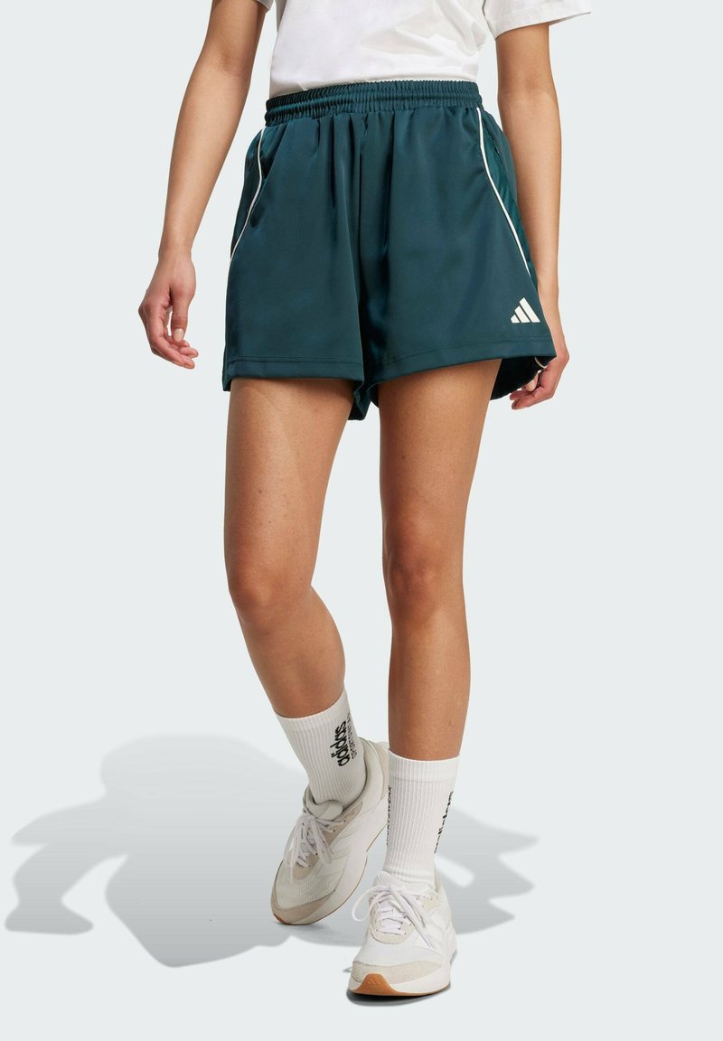 Tyrkysové sportovní šortky s bílými bočními pruhy, vyrobené z lehké látky. Mají elastický pas a jsou nošeny s bílými ponožkami a teniskami.