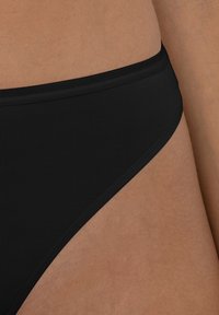 Zwarte bikini onderkant met een gladde, geribbelde textuur en een low-rise ontwerp. Bevat minimalistische stiksels en een klassieke snit.