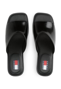 Svarte slip-on sandaler med en blank overflate og en bred stropp over toppen. Har polstrede såler og en logo i rødt, hvitt og blått.