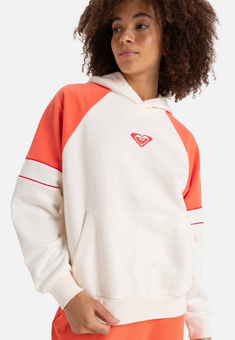 Hooded sweatshirt in cream and orange with a front pocket. Features raglan sleeves, red accent stripes, and a small logo on the chest.