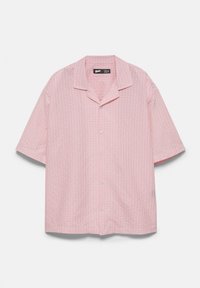 Chemise à manches courtes boutonnée avec un motif à carreaux rose et blanc et col camp, présentée sur un fond uni.