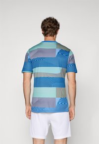 Korte mouwen sportshirt met een meerkleurig geometrisch patroon in tinten blauw, groen en grijs, met een ronde hals.