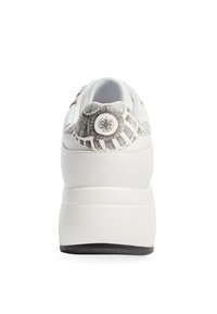 Białe sneakersy z teksturowanym szarym i czarnym wzorzystym tyłem, z okrągłym emblematem, zaokrąglonym noskiem i grubą podeszwą.