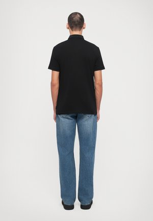 Svart polo-skjorte med korte ermer, laget av bomull, har en tettsittende design. Sammen med lyseblå løse rett skjørte.