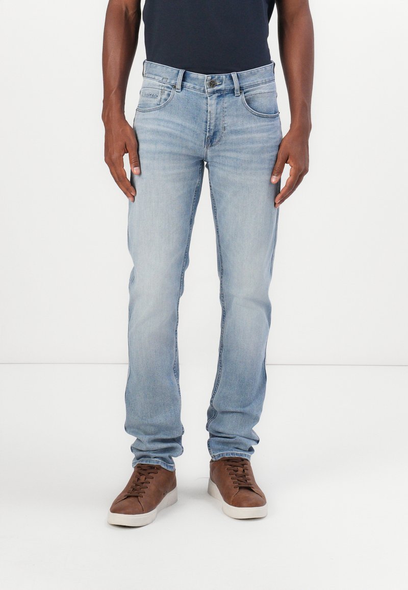 Jeans en denim bleu clair avec une coupe droite, dotés de poches avant et arrière, et d'une accentuation en cuir noir. Matière en coton.