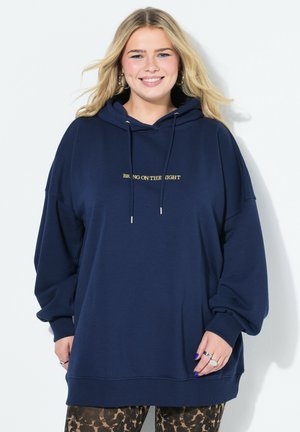 Marineblauwe oversized hoodie van zacht stof met een trekkoord kap. Voorzien van gouden tekst "BRING ON THE NIGHT" op de voorkant en geribbelde manchetten.
