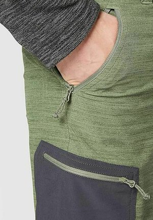 Pantaloni di stoffa verde con un pannello grigio. Le caratteristiche includono una tasca con zip sul lato e una texture liscia con un leggero elastico.