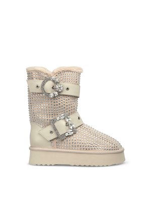 Stivale alla caviglia beige con decorazioni in strass, bordo in pelliccia sintetica, design a doppia fibbia, suola scolpita e tomaia texturizzata.