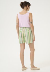 Violet beželsvarkis, derinamas su dryžuotais žaliais ir pastelinių spalvų šortais, turinčiais elastinį liemenį ir užpakalines kišenes. Apsirengta su kreminėmis basutėmis.