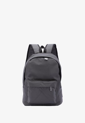 Sac à dos en tissu gris avec une forme arrondie, fermeture à double zip, poche avant et bretelles noires réglables. Design minimaliste sans motifs.