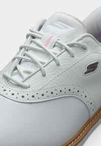 Baskets en cuir blanc avec des superpositions texturées, des accents perforés et des lacets ton sur ton, avec une étiquette rose "Prestige" sur la languette.