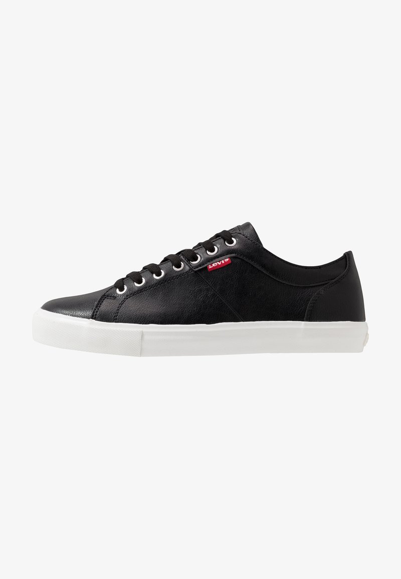 Black leather sneaker with a white rubber sole, featuring black laces and a small red Levi's logo on the side. Smooth texture and low design.