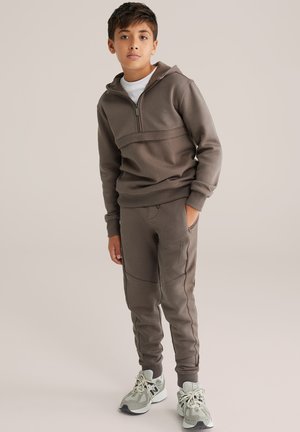 Bruine ritssluiting hoodie met een textuurpaneel en bijpassende smalle joggers. Gedragen met lichte sneakers met mesh-accenten.