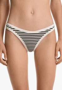 Bikini donji dio u crno-bijelim prugama s mekanim elastičnim pojasom. Ima uske bočne trake i glatku teksturu.